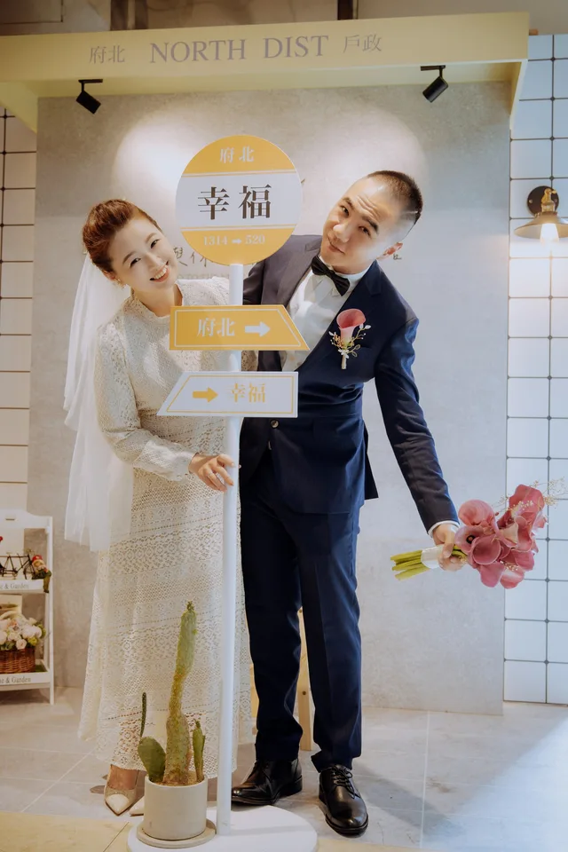 白富美結婚登記攝影作品,新人穿著婚紗與西裝,手持幸福指示牌合照